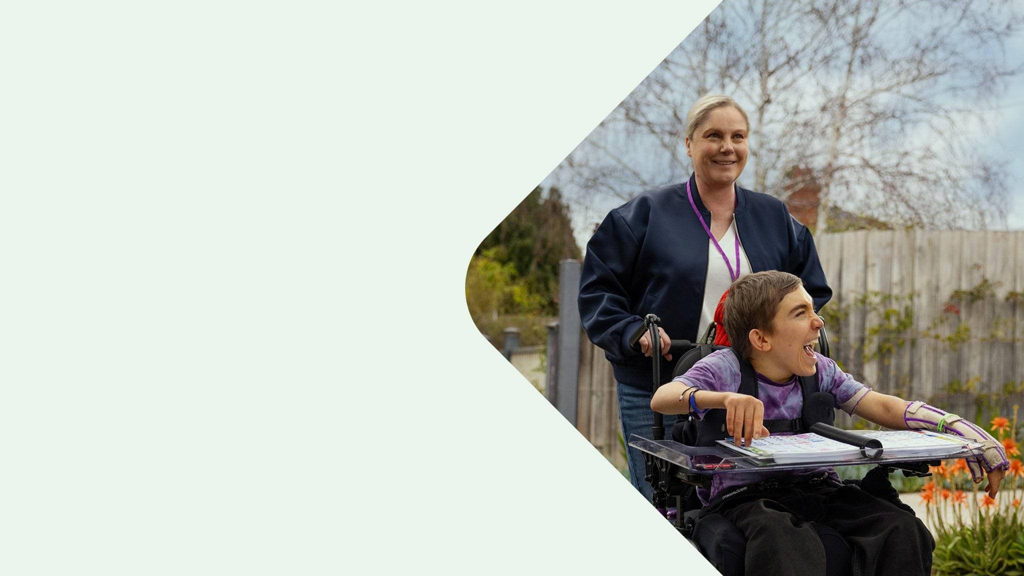 Community services carer pushing a young client in a wheelchair.